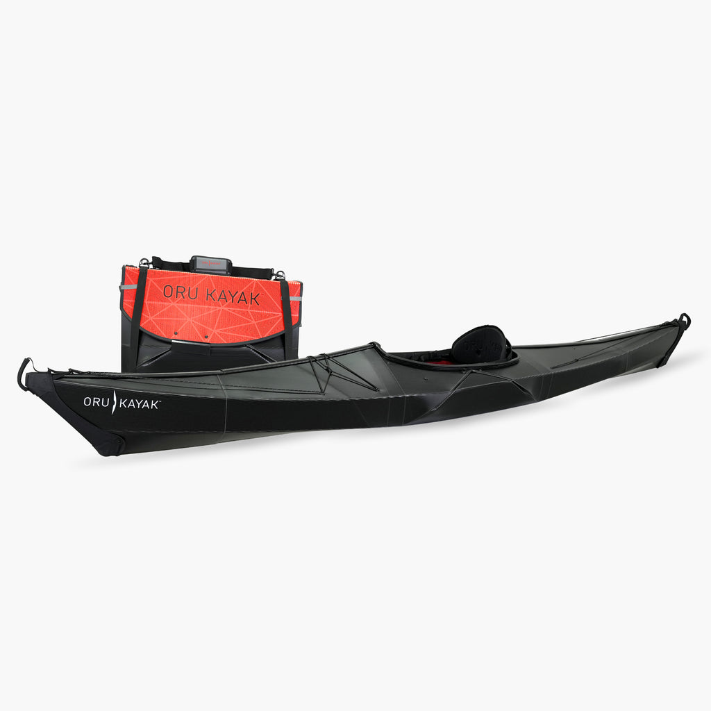Side view of the Oru Kayak Bay model in black, shown fully assembled in front of its compact folded box form.