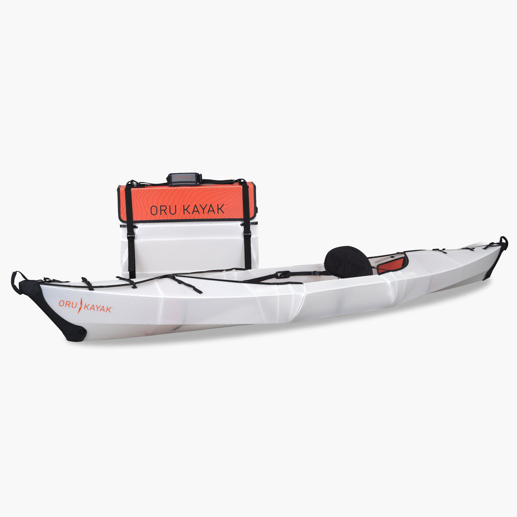 Side view of the Oru Kayak Beach model in white, shown fully assembled in front of its compact folded box form.